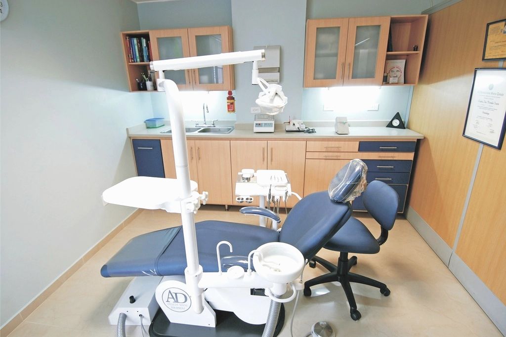 A bright, tidy treatment room with a reclined chair and clear worktops.