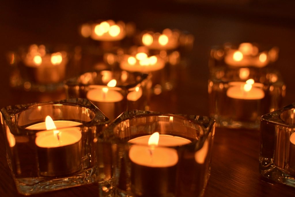 Rows of lit candles glowing warm amber against the dark