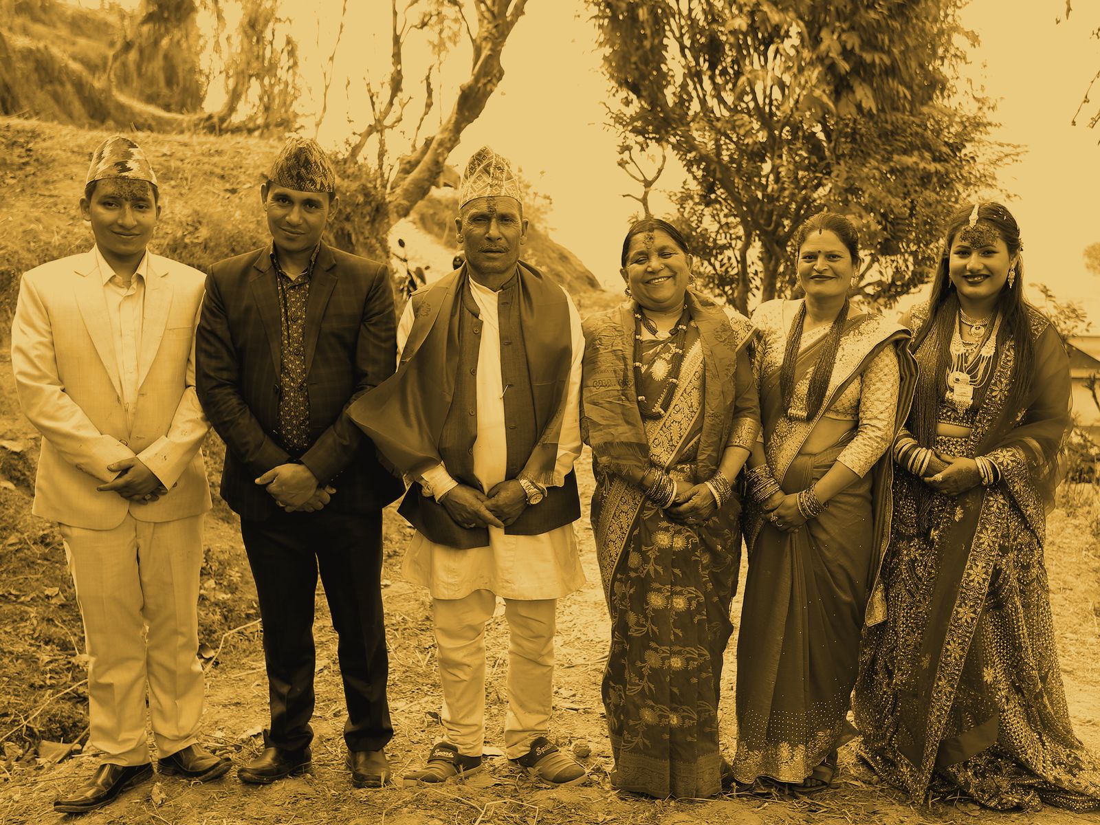 A wedding family group posed in a line, smiling at the camera