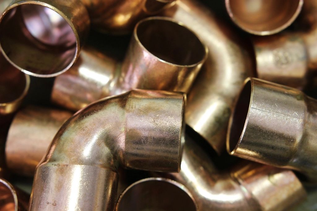 Close-up of copper elbow pipe fittings, stacked loose